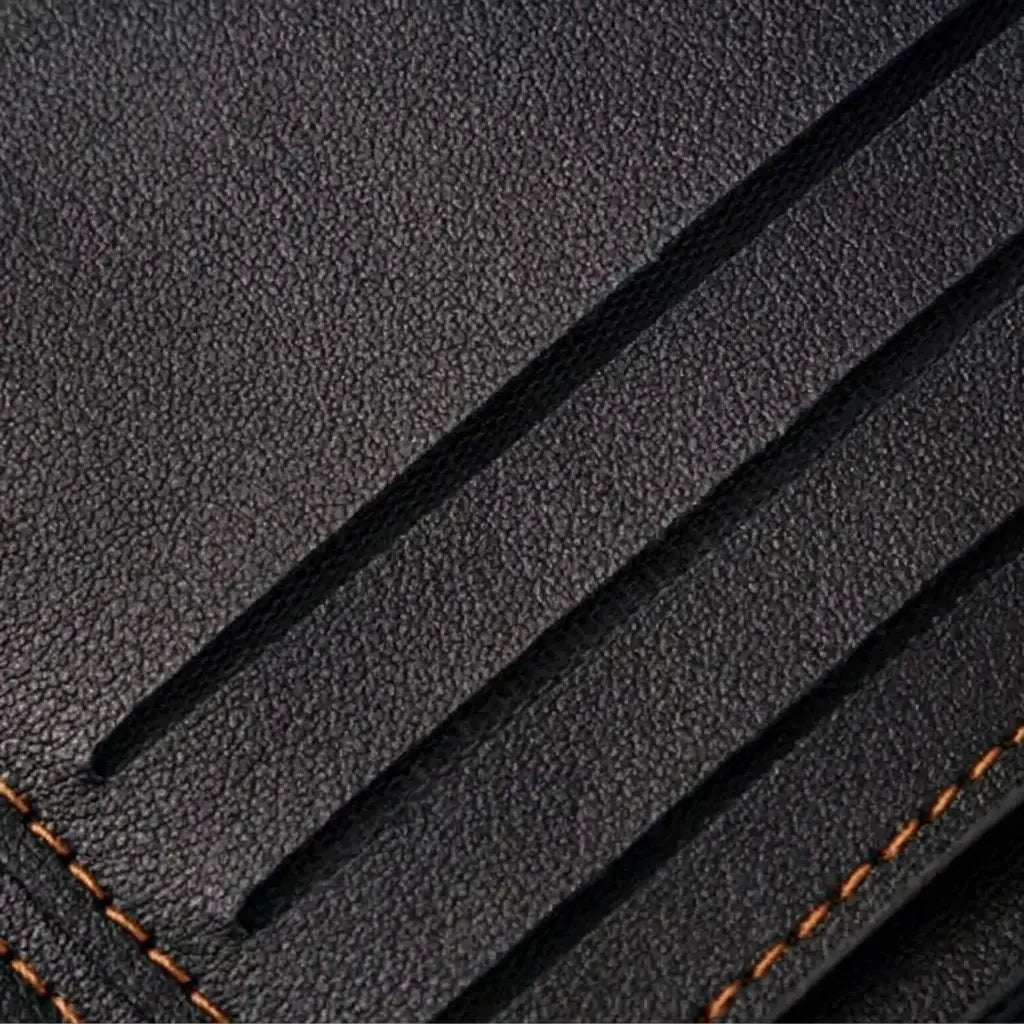 Extreme close-up of the Arlen wallet's interior, showcasing the high-quality pebbled black leather texture and the precision of the tan reinforced stitching on the card slots.