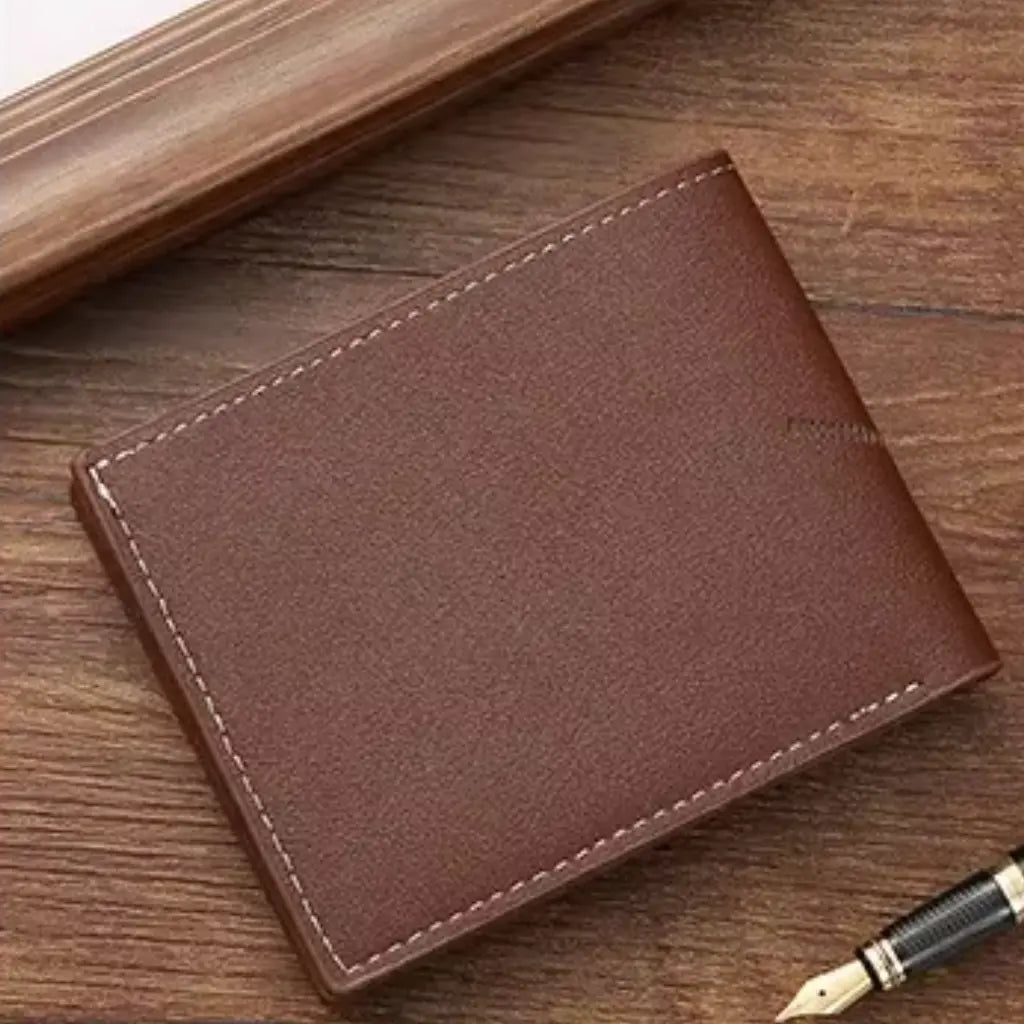 Back view of the brown slim wallet on a wooden surface, with a pen nearby.